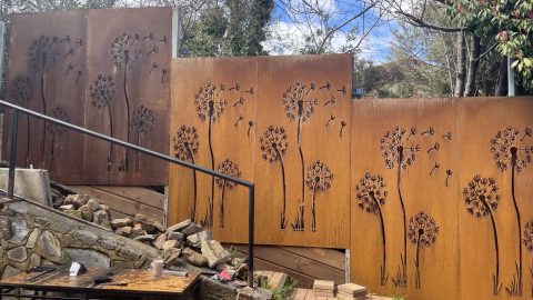 Dandelion metal art panels in garden setting.