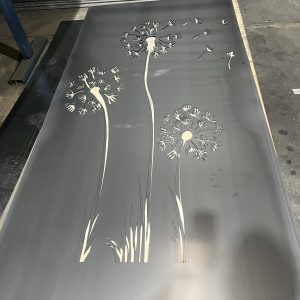 Metal panel with dandelion design cutouts.