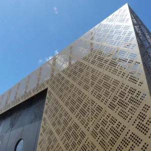 Modern building with perforated facade against blue sky.
