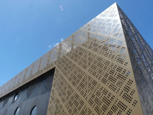 Modern building with perforated facade against blue sky.