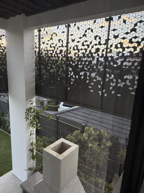 Decorative privacy screen with outdoor view and plants.