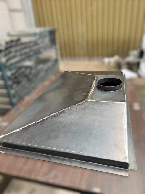 Rectangular metal box with round hole on table.